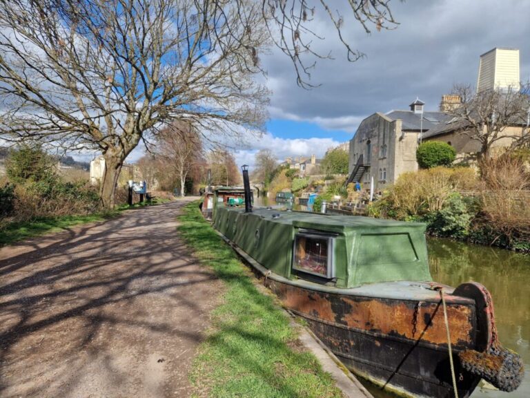 A canal boat moored under a tree next to a tow path in the city of Bath
