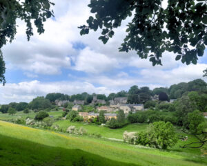 Photo of a quaint village in the distance nestled between rolling hills