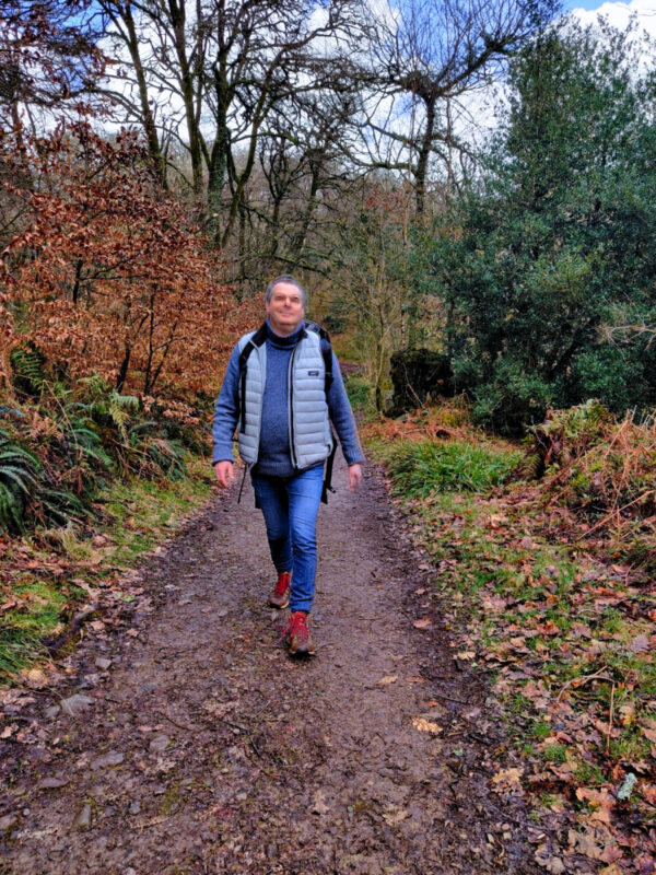 A walker walking down a footpath in a wood in Exmoor