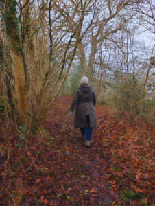 A person walking through woods in the Cotswolds in winter