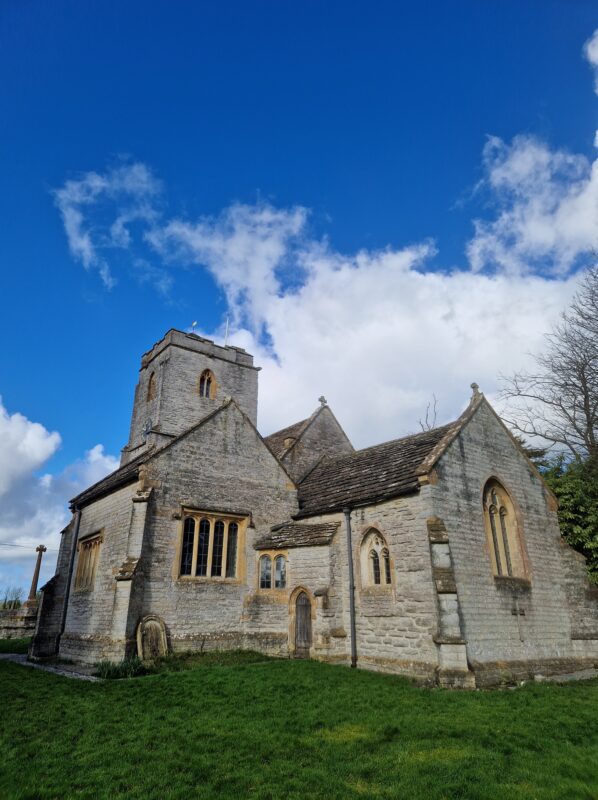 View of a Norman village church under a bright blue sky