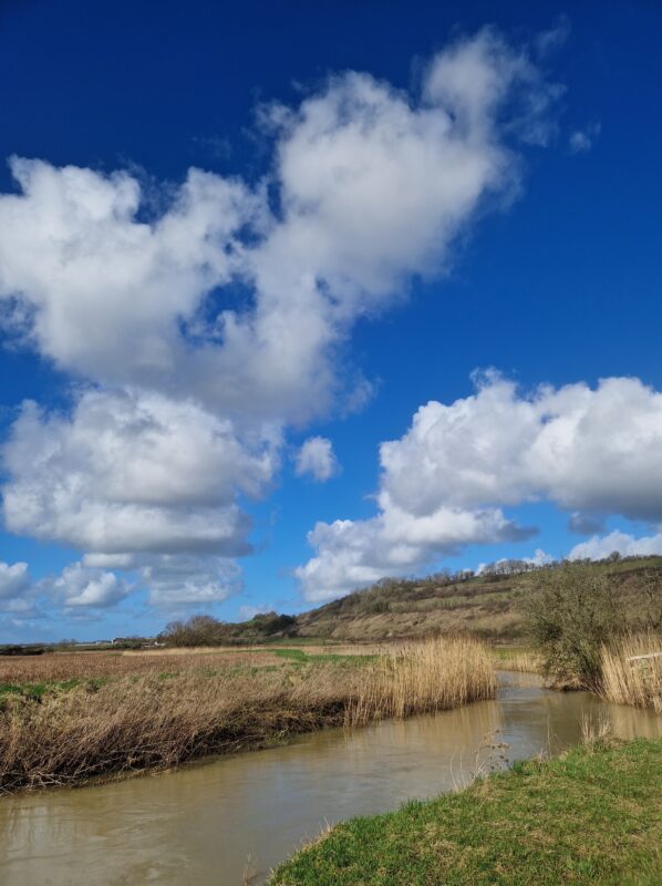 View of a bend in a river with a blue sky and white clouds