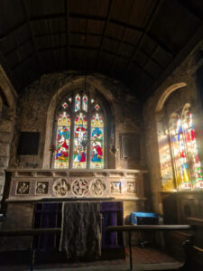View of an old church altar lit by light falling through stained glass windows