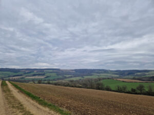 A view over a stubble field with green fields stretching off into the distance
