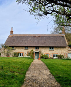 Garden path leading up to a large thatched cottage