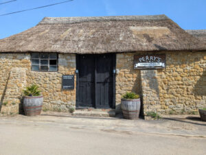 Photo of a traditional Somerset cidery. An ancient brick building with a thatched roof.