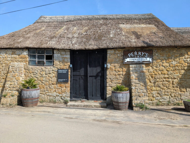 Photo of a traditional Somerset cidery. An ancient brick building with a thatched roof.