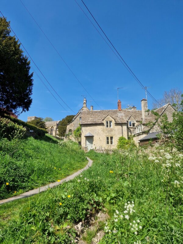 A footpath leading through a green field to a cottage