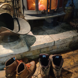 Two pairs of hiking boots in front of a log fire