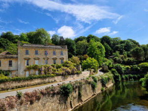A grand manor house nestled in a valley next to a river