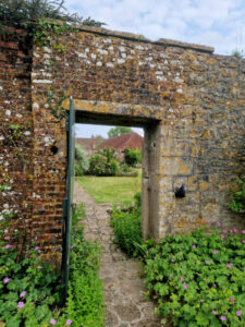 Old stone doorway with the door open showing a stone path leading out into a walled garden.