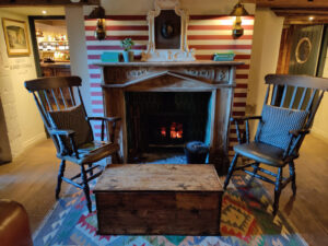 Two wooden chairs in front of a lit fireplace in a country inn