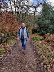 A person walking down a track surrounded by autumnal trees