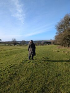 A female walker standing in a field with her back to the camera