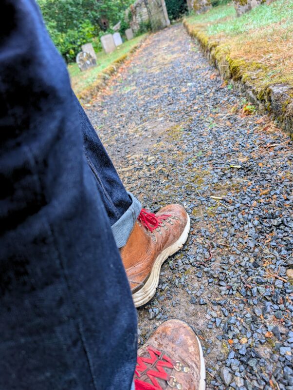 Photo of a walker's legs with brown leather hiking boots and red laces