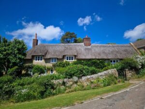 A traditional thatched cottage next to a village road