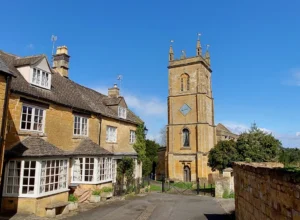 A traditional English village with a row of cottages to the left and a path leading up to the village church