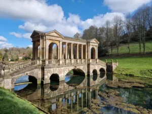 An ornate Palladian bridge over a river in a grand country garden in the city of Bath in South West England.