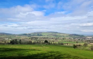 Rolling Cotswolds countryside with a patchwork of fields stretching off into the distance.