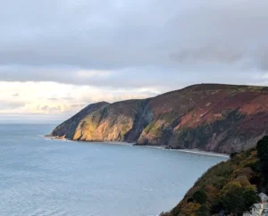 A rugged coastal scene with steep cliffs descending into a gray sea on the Exmoor section of the South West Coast Path.