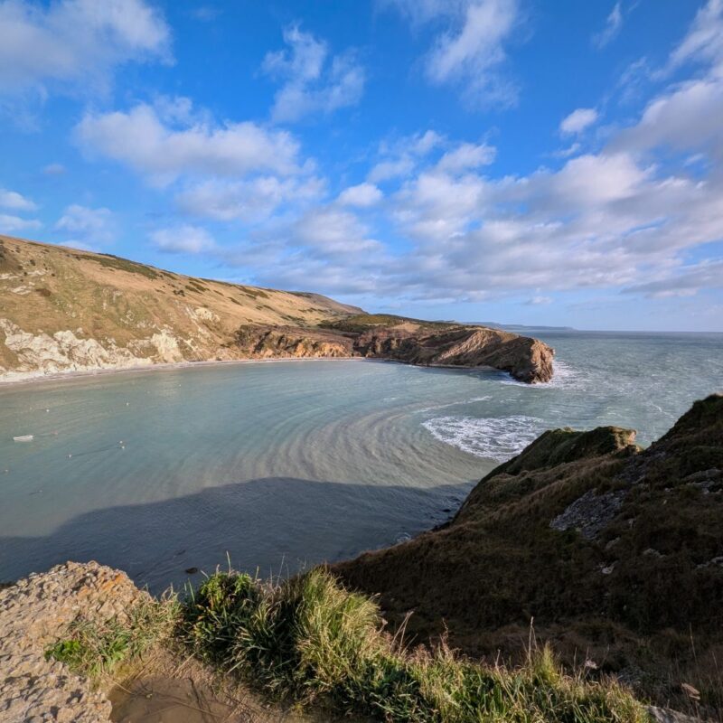 Image of Lulworth Cove taken from a clifftop, the almost spherical bay surrounded by steep cliffs