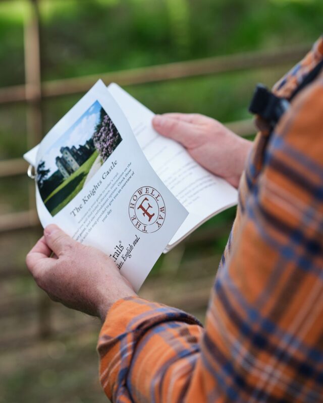 A person holding a trail guide with step-by-step instructions for a walk.
