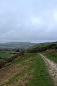 A chalk footpath cuts through the landscape with hills stretching into the distance and a castle in the distance