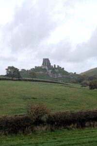 A dramatic ruined castle sits on top of a hill surrounded by countryside