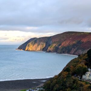 A rugged coastline of cliffs stretching off into the distance lit by the setting sun.