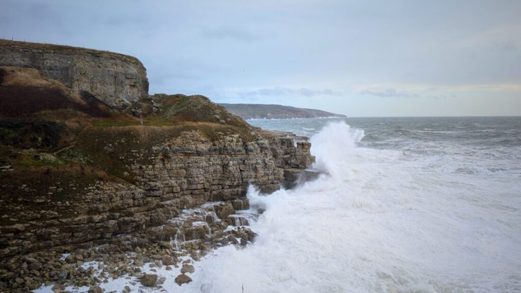 Jagged cliffs on the Dorset coast with waves crashing high up against the rocks.
