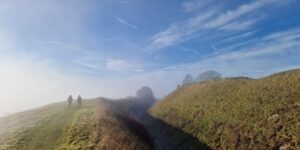 Two figures walking beside earthworks of an Iron Age hillfort.