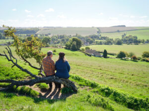 David and Alison Howell take a rest on a tree trunk in the middle of the English countryside on a hike