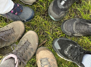 Friends and family put their hiking boots in a circle on the ground