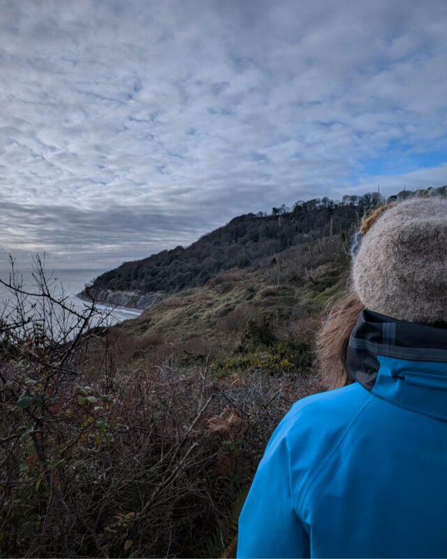 View of a hiker looking out over the Dorset cliffs and sea.