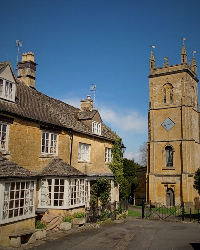 View of a church and cottages in the Cotswolds on a sunny day.