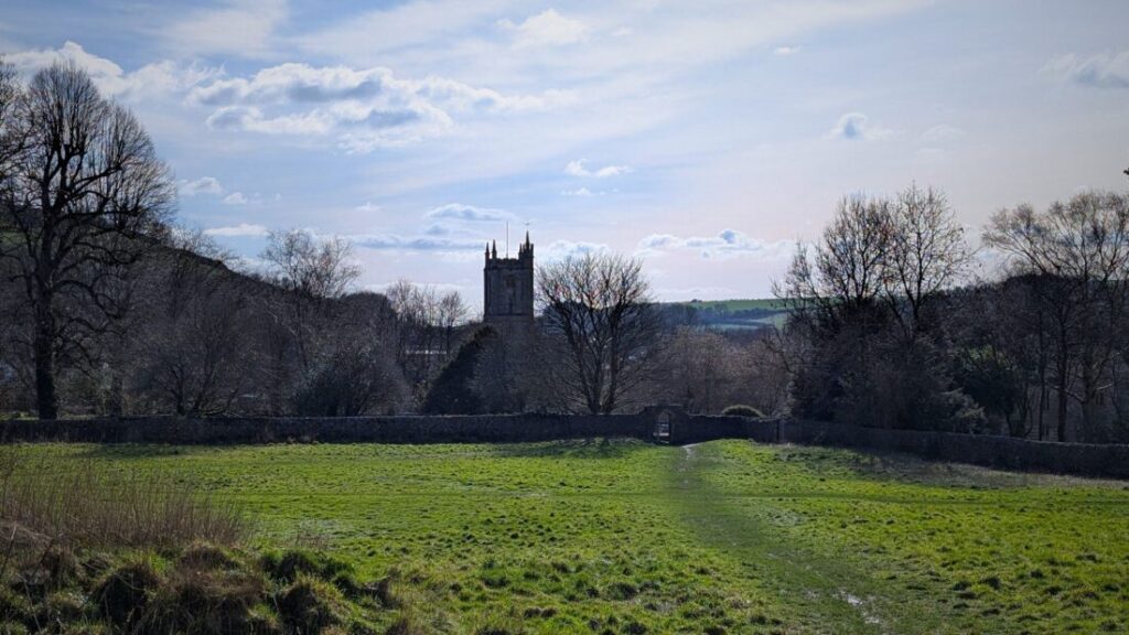 View of a footpath leading over a field and towards a church in the distance