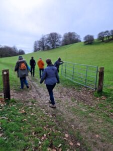 The Foot Trails team out in the countryside, entering a field through a metal gate.