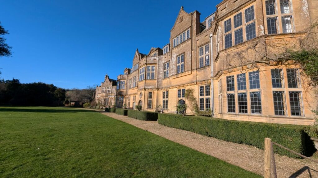 View of a grand country estate with a footpath and lawn in front of it.