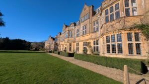 View of a grand country estate with a footpath and lawn in front of it.