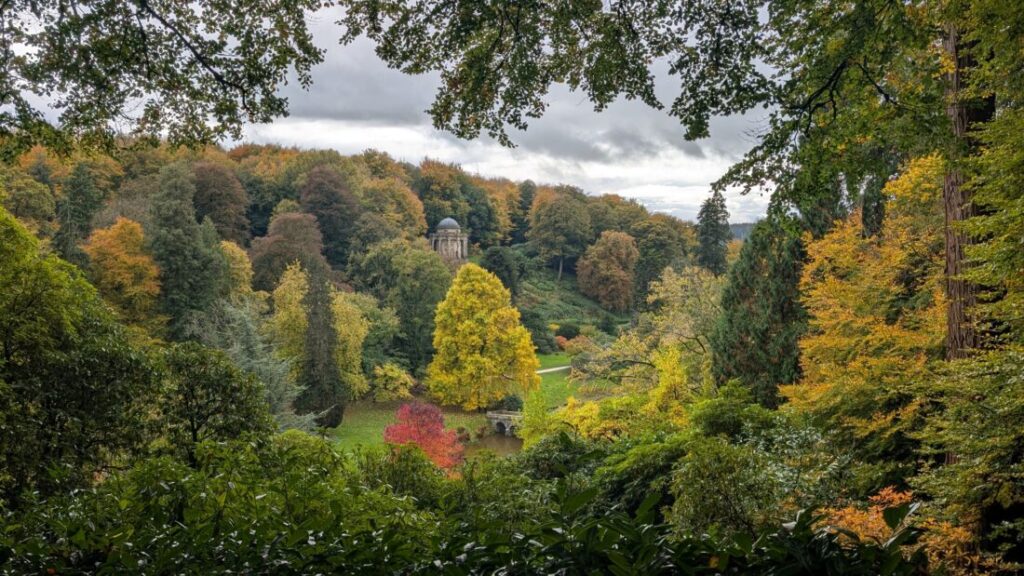 View of the Stourhead estate in autumn with the temple of apollo in the distance.