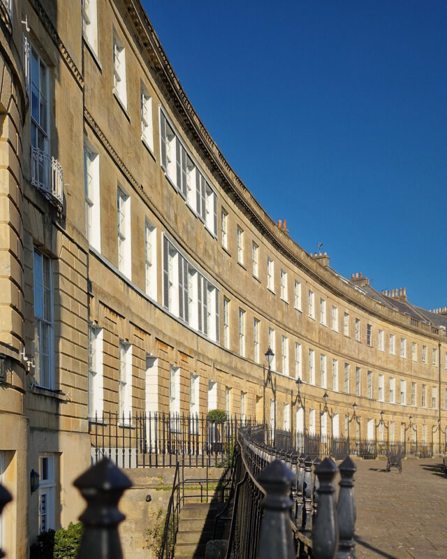 A row of elegant Georgian town houses in Bath curving off into the distance.