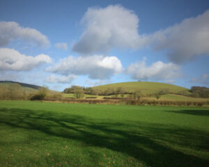 View over rolling green countryside with hills and trees in the distance