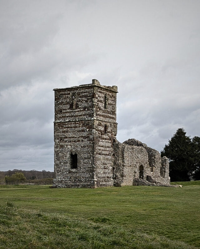 View of the ruins of a 12th century church standing alone in a field.