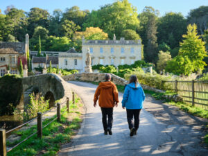 David and Alison Howell walking over a bridge towards a beautiful country house