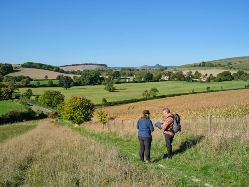 Two hikers have stopped on a trail and are consulting a map