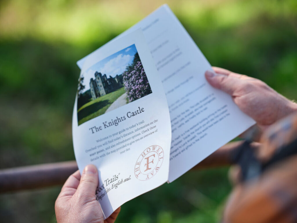 Close up of a pair of hands holding a Foot Trails trail guide in the countryside