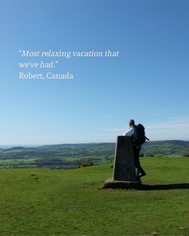 Image of Foot Trails Co-Founder David Howell standing at a trig point on top of a hill and looking of into the distance. There is a quote on the image that says 'Most relaxing vacation that we've had. Robert, Canada