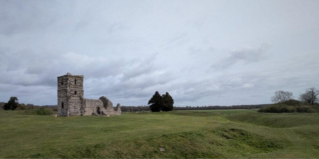 The ruins of a 12 century church set amongst rolling green fields, with no other buildings around.