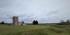 The ruins of a 12 century church set amongst rolling green fields, with no other buildings around.
