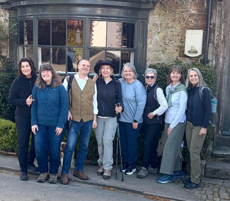 Foot Trails Co-Founders Alison and David Howell standing in a group of six female hikers smiling and laughing at the camera.